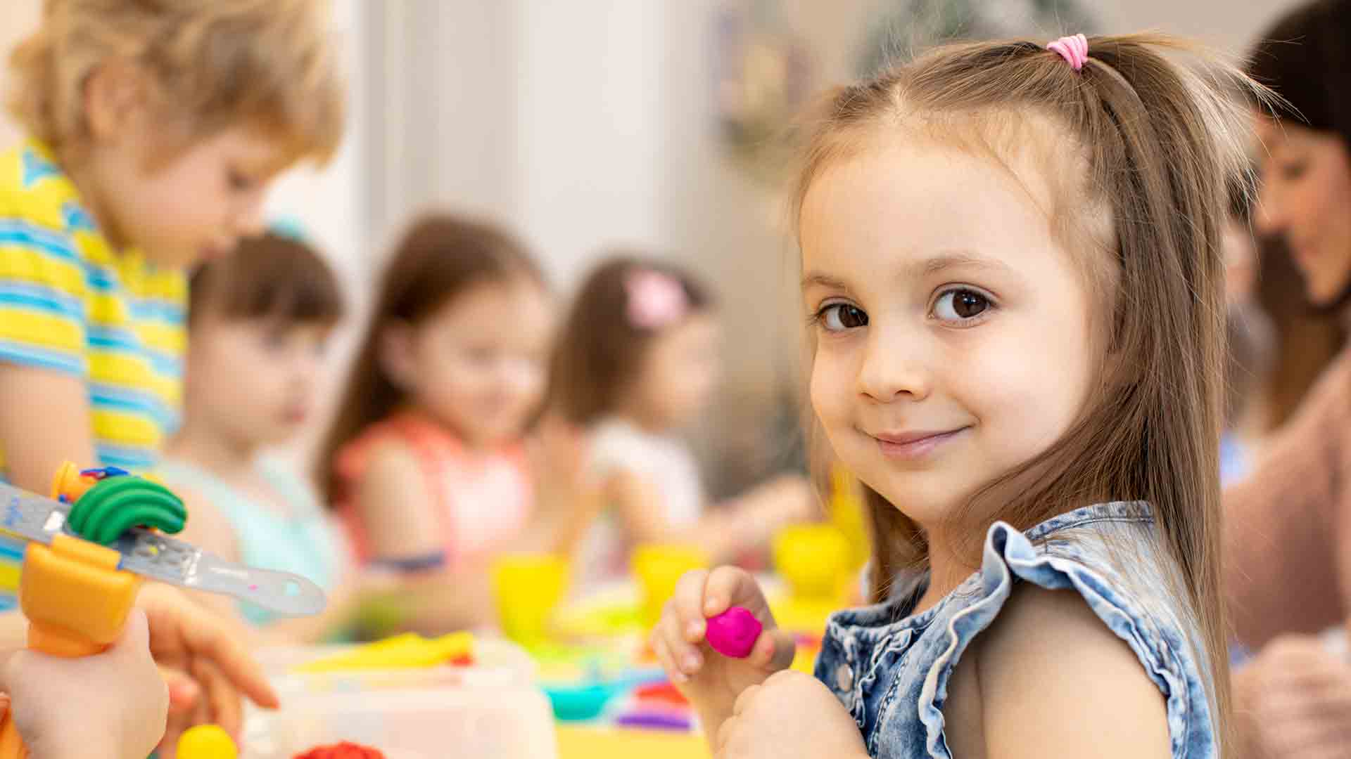 Happy kids playing with playdoh in a daycare center